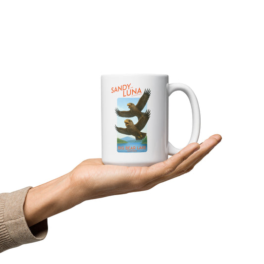 White mug with eagle design held in a hand on a white background