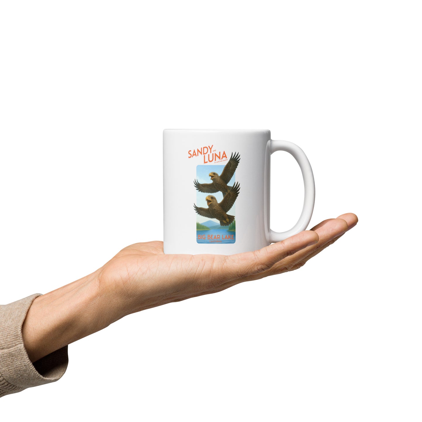 White mug with bird design held in a hand on a white background