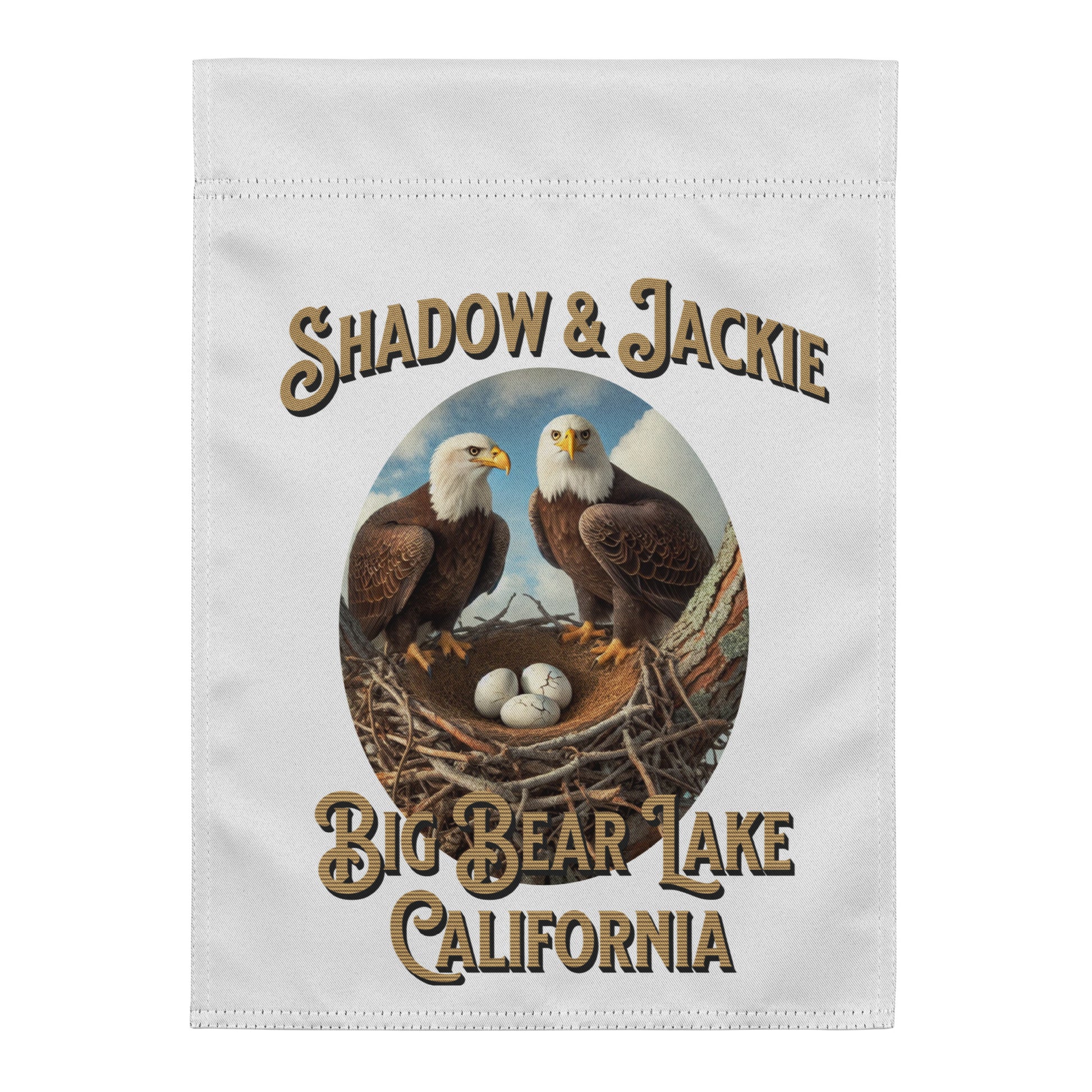 A white rectangular fabric item, likely a towel or flag, featuring a printed graphic of two bald eagles at a nest with the text 'SHADOW & JACKIE' above and 'BIG BEAR LAKE CALIFORNIA' below.