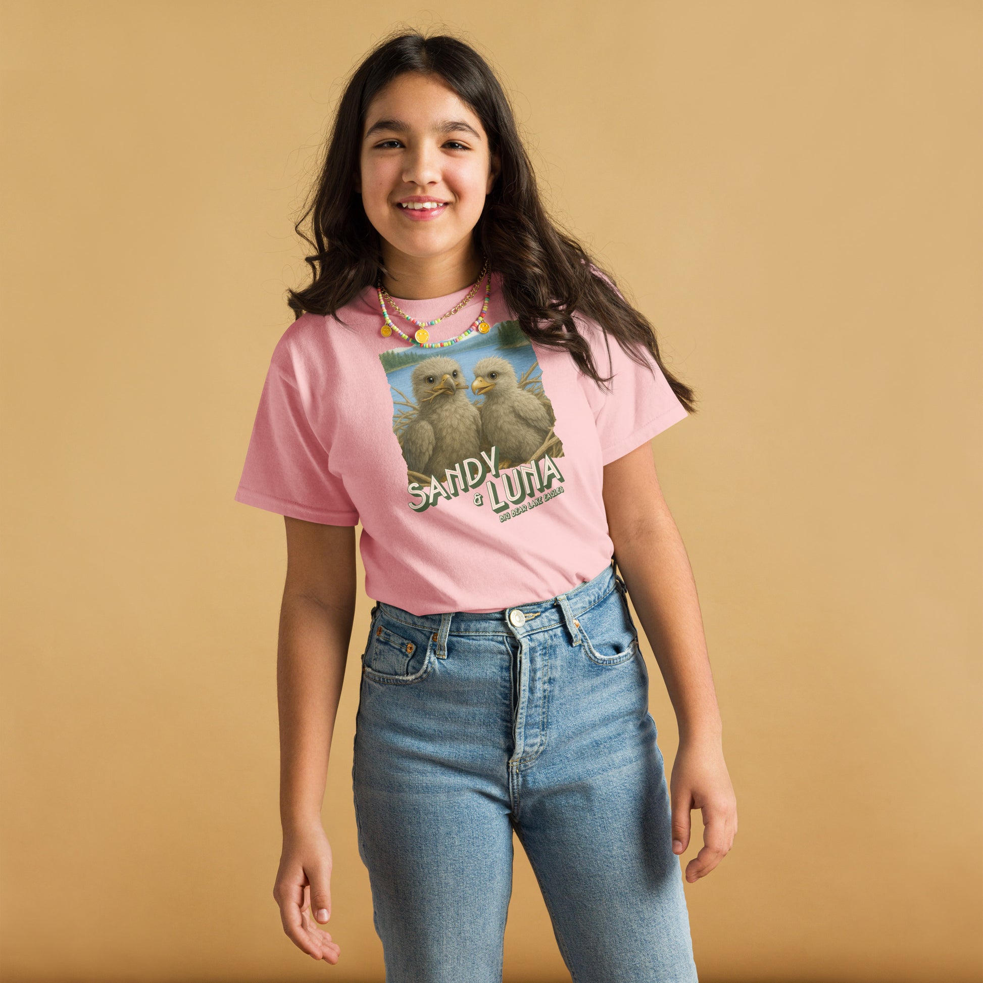 Young girl wearing a pink t-shirt with a graphic design on a beige background